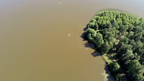 Tiny-boat-speeding-through-calm-lake-of-Poland,-aerial-drone-view
