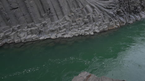 Bubbles-in-green-water-river-flowing-between-twisted-basalt-columns