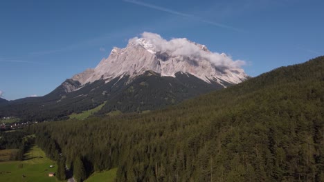 Imágenes-De-Drones-Que-Se-Acercan-A-La-Montaña-Más-Alta-De-Matterhorn-Alemania-Con-Bosques-En-Primer-Plano-Y-Cielos-Azules-Y-Nubes