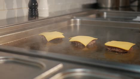 Melting-cheese-on-delicious-cooking-burger-patties-on-hot-restaurant-stove