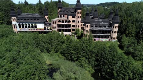 Lapalice-castle-surrounded-by-dense-forest,-aerial-fly-away-from-tower-to-far-distance