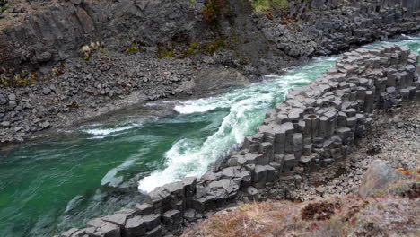 Slow-motion-establishing-shot-of-green-water-river-flowing-in-spectacular-basalt-canyon-in-Iceland