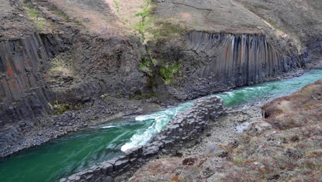 Wide-establishing-shot-of-a-basalt-canyon-with-a-green-water-river