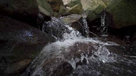 Slow-motion-tracking-shot-of-a-small-stream-flowing-down-rocks