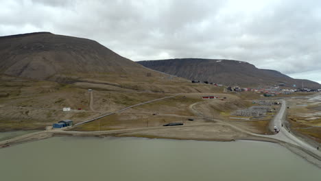 Backwards-drone-flight-in-Svalbard---revealing-Longyearbyen-city-on-left-side