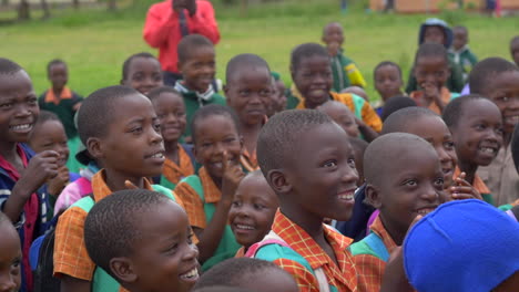 A-Crowd-of-African-Children-Jumping-and-Smiling-as-a-few-American-Visitors-Teach-Them-a-Song,-Slow-Motion-Close-Up