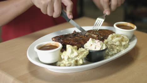 Man-Slicing-and-Eating-Pork-Ribs-with-Mashed-Potato-and-Vegetable-Salad-Side-Dish
