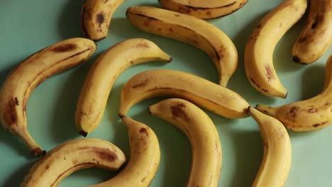 Una-Toma-Macro-De-Plátanos-Orgánicos-Amarillos-Maduros-Girando-Contra-Un-Fondo-Verde