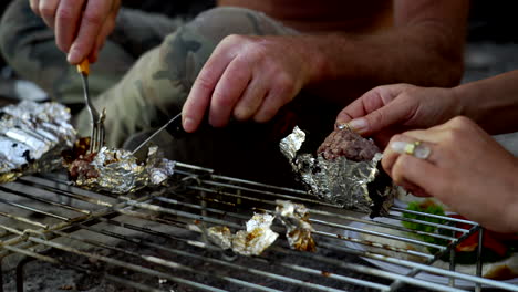 Cooking-burgers-wrapped-in-aluminum-foil-in-a-fireplace