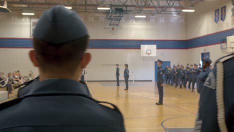 Rückansicht-Canadian-Air-Cadets-Aufgereiht,-Während-Andere-Kadetten-Die-Turnhalle-Im-Hintergrund-Betreten-Und-In-Formation-Marschieren