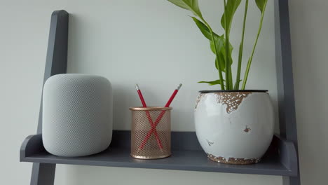 Static-Shot-of-Man-Tapping-Twice-with-Pause-an-Apple-HomePod-on-top-of-Modern-Looking-Bookshelf-adjacent-to-a-Pencil-Holder---Plant