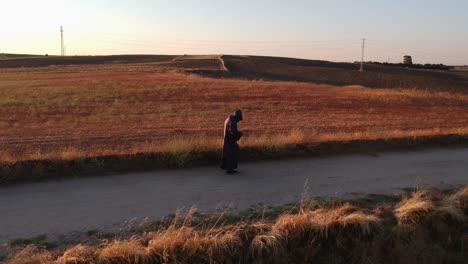 A-shot-from-low-height-following-sideways-a-monk-walking-on-a-dirt-road