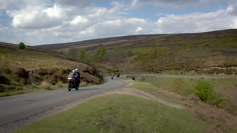 Motorcyclists-sweep-through-a-sharp-bend-on-a-narrow-moorland-road