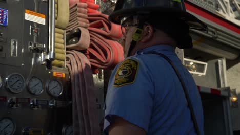 Firefighter-works-around-gear-and-fire-hoses-on-a-fire-truck-early-in-the-morning-to-prep-for-emergency-response