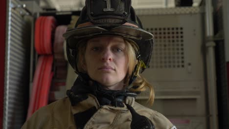 Female-firefighter-in-protective-helmet-and-firefighting-coat-looks-at-camera