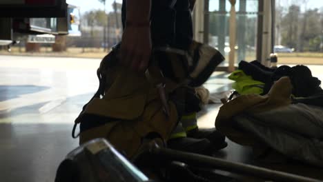 Der-Feuerwehrmann-Zieht-Eine-Schützende-Feuerwehrhose-An,-Während-Er-Sich-Darauf-Vorbereitet,-Auf-Einen-Notfall-Zu-Reagieren
