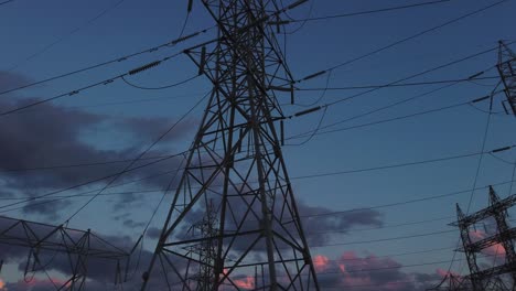 Wide-pan-and-tilt-up-to-electrical-towers-against-the-sky-at-day's-end