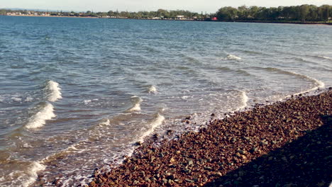 Ocean-waves-wash-over-Brown-rocks-near-Woody-Point-Jetty-on-a-cold-sunny-morning