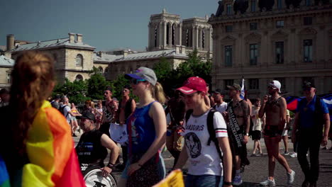 A-small-group-of-people-at-the-Pride-parade-marching-on-the-bridge-at-Chatlet-with-the-Notre-Dame-Church-in-the-background-after-the-fire