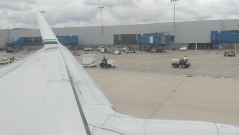 Looking-out-the-window-over-the-wing-of-an-airplane-as-it-rolls-back-to-prepare-for-take-off,-Detroit-Metro,-DTW,-cloudy