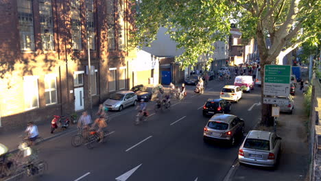 Large-group-of-cyclists-protesters-come-round-a-bend,-followed-by-police-cars-in-the-back