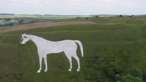 Aerial-Clockwise-Orbit-of-the-Westbury-White-Horse-on-a-Summer’s-Day-with-Hikers-Walking-Around-Perimeter-of-Horse---Revealing-the-Car-Park-with-Narrow-Crop