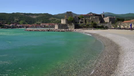 Collioure-beach-and-castle-on-a-hot-and-windy-day-with-wind-whipping-water-off-the-sea-in-the-bay