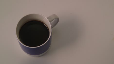 Kaukasische-Hand,-Die-Laktosefreie-Milch-In-Eine-Blaue-Tasse-Kaffee-Gießt
