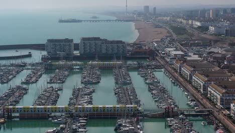 Aerial-pan-up-reveal-from-Brighton-Marina-to-the-Beach,-Pier---I360-attraction-on-the-coast-of-Southern-England