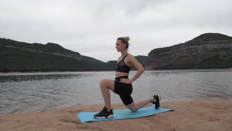 Fit-women-stretching-her-left-leg-next-to-a-lake