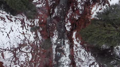 Aerial-Top-Down-flying-backward-shot-of-a-River-stream-in-the-valley-covered-with-snow-during-the-winters-in-Manali,-Himachal-Pradesh-shot-with-a-drone-in-4k