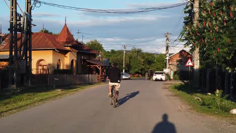 Moreni,-Romania---13-July-2020-:-Guy-wearing-black-riding-bike-on-a-country-road-at-sunset,-slow-motion