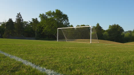 A-wide,-low-angle-dolly-of-an-empty-soccer-field-on-a-sunny,-summer-morning