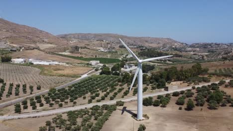 Wind-Turbines-In-A-Wind-Farm-With-Olive-Groves-Growing-In-The-Field-On-A-Sunny-Day-In-Agrigento,-Sicily,-Italy