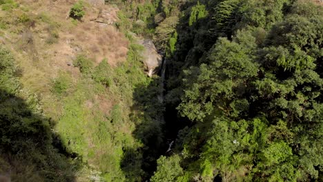 Aerial-Dolly-Zoom-In-shot-of-a-Beautiful-huge-plunge-waterfall-covered-with-trees-in-Bir,-Himachal-Pradesh,-shot-with-a-drone-in-4k