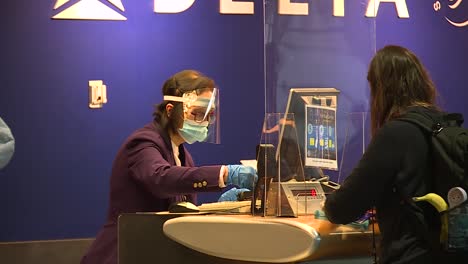 WOMAN-CHECKING-IN-AT-AIRPORT-WEARING-MASK-DURING-COVID-19