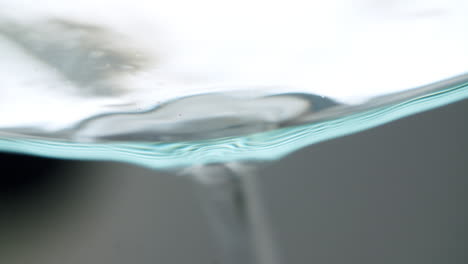 Abstract-macro-shot-of-water-dropping-out-of-a-glass