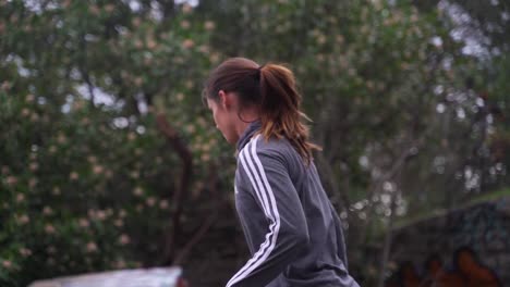 Girl-in-hoodie-looking-down-at-soccer-ball-while-dribbling,-slow-motion