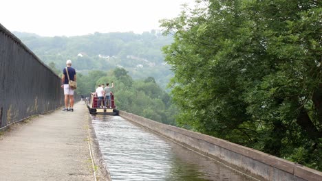 British-tourist-steering-narrow-canal-boats-on-landmark-Pontcysyllte-Aqueduct-Welsh-countryside-waterway