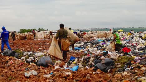 Impoverished-people-carry-large-sacks-to-fill-while-scavenging-in-a-garbage-dump-in-Brazil