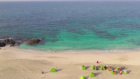 Oman-tourism-turquoise-beach-with-camping-tents-aerial
