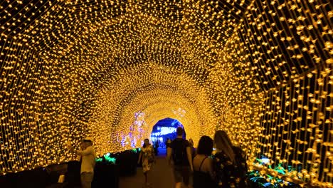 Walking-Inside-The-Illuminated-Tunnel-Made-Of-Yellow-Christmas-Lights-During-The-Winter-Wonderland-Event-At-Gardens-By-The-Bay-In-Singapore-At-Night