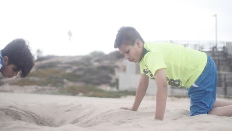 Two-Young-Kids-Dig-Together-on-Beach-Field-Trip,-Slow-Motion-Reveal-Shot-Move-Left