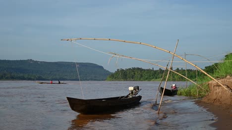 Langes-Boot,-Das-Den-Mekong-Von-Thailand-Nach-Laos-überquert,-Während-Zwei-Andere-Boote-Auf-Schlammigem-Braunem-Wasser-Hüpfen,-Während-Sie-Am-Thailändischen-Flussufer-In-Huai-Phai,-Ubon-Ratchathani,-Festgemacht-Sind