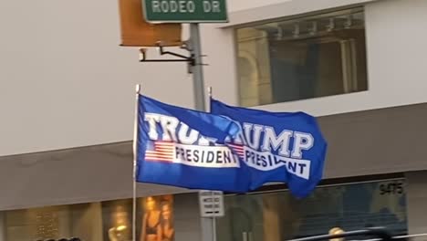 Trump-flags-flying-in-the-wind,-off-of-a-truck,-Rodeo-Drive,-Beverly-Hills
