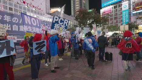 Japanese-People-Protesting-Against-Wearing-Of-Mask-And-PCR-Test-In-Shibuya-On-Halloween-Night---Coronavirus-Protest-In-Tokyo,-Japan---side-view-shot