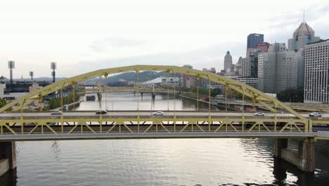 Aerial-turn-reveals-yellow-bridge-over-river-in-Pittsburgh