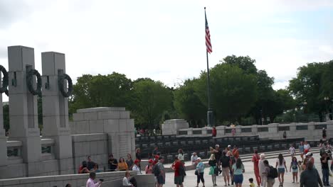 Crowds-Sightseeing-With-America's-National-Flag-Waving-Against-Bright-Sky-At-World-War-II-Memorial-In-Washington-DC,-United-States