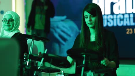 Nervous-Female-Musician-Playing-Drums-With-Serious-Facial-Expression-During-A-Musical-Show---medium-shot