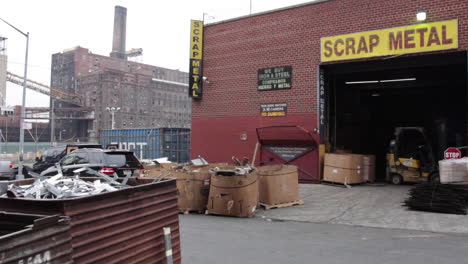 Brooklyn-Industrial-Scrap-Metal,-Biker-Drives-By,-Forklift-Operator-Employee,-Domino-Sugar-Factory-in-Background